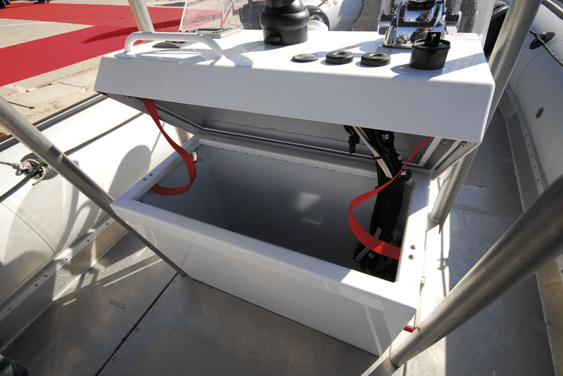 Le haut de la console de pilotage bascule, dévoilant un grand coffre étanche.
