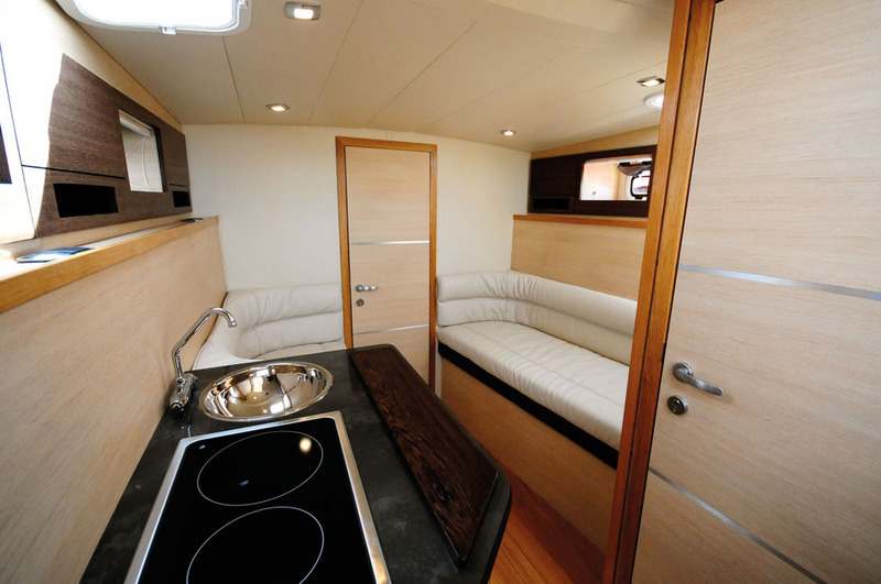 Le carré central spacieux, avec cuisine sur bâbord, et porte vers la cabine double avant. La banquette tribord offre un lit d'appoint de bonne taille.