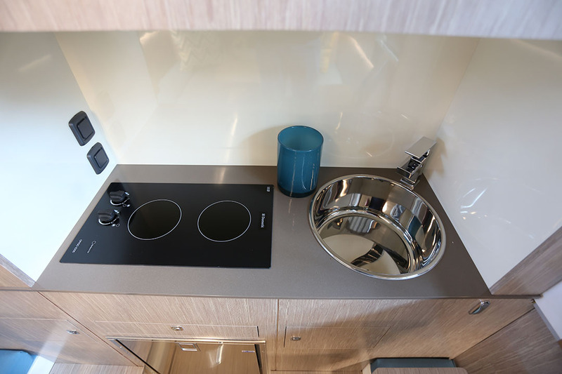 La cuisine se trouve dans la cabine arrière. Elle comporte un frigo, une plaque de cuisson deux feux à induction, un évier inox et des rangements.