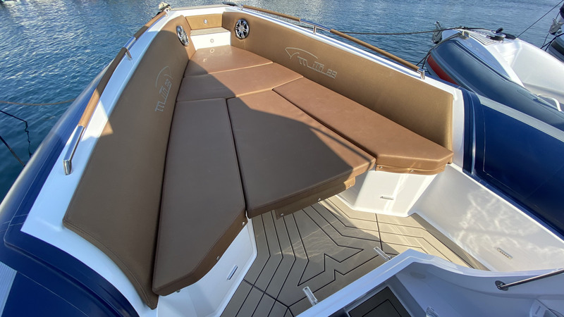 Beau travail de sellerie pour le solarium avant, bordé de mains courantes gainées et de dossiers brodés au nom du bateau. 