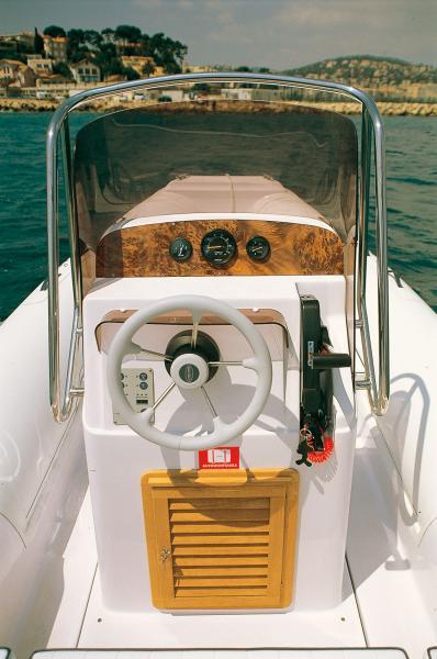 Le pare-brise très protecteur qui surmonte la console est encadré par une robuste main-courante en inox. Notez aussi la porte en teck du rangement de console.